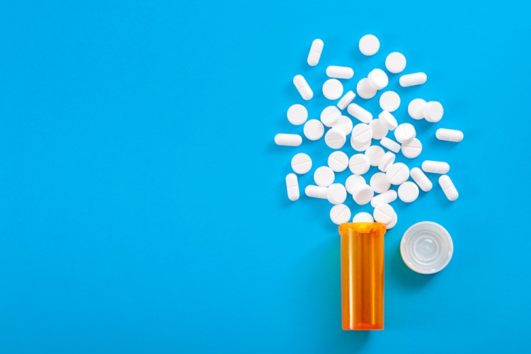 Pill bottle spilling white tablets on blue background stock image