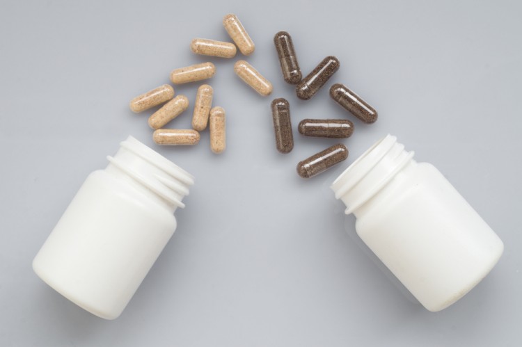 Drug capsules spill out of a two white plastic bottles